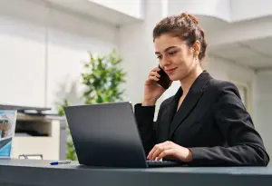 Medewerker is aan het bellen terwijl ze typt op de laptop